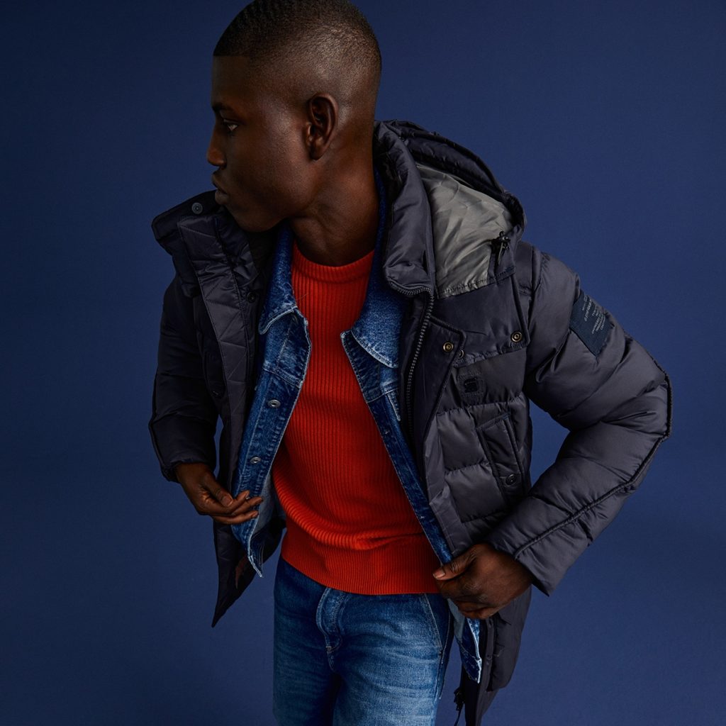 A man wearing a layered G-Star RAW outfit looks away.