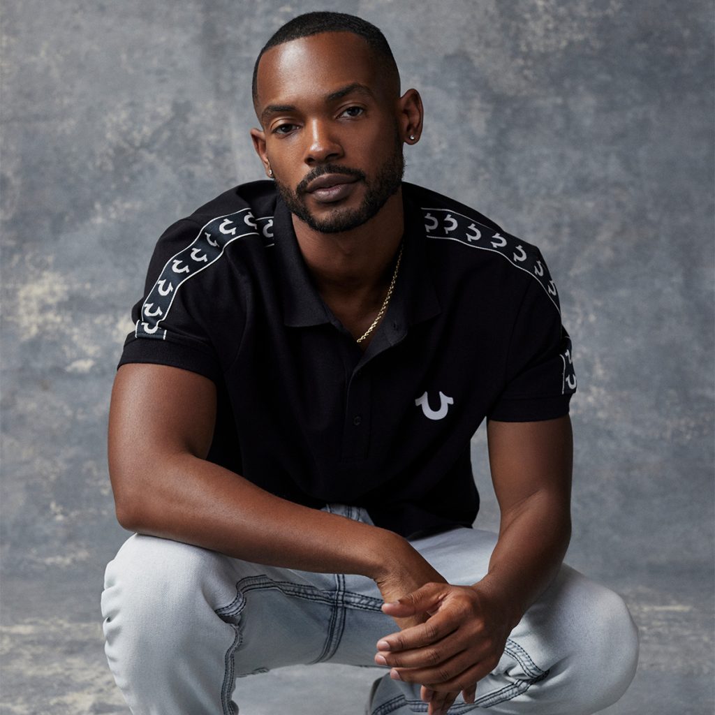 A man wearing True Religion clothing crouching down