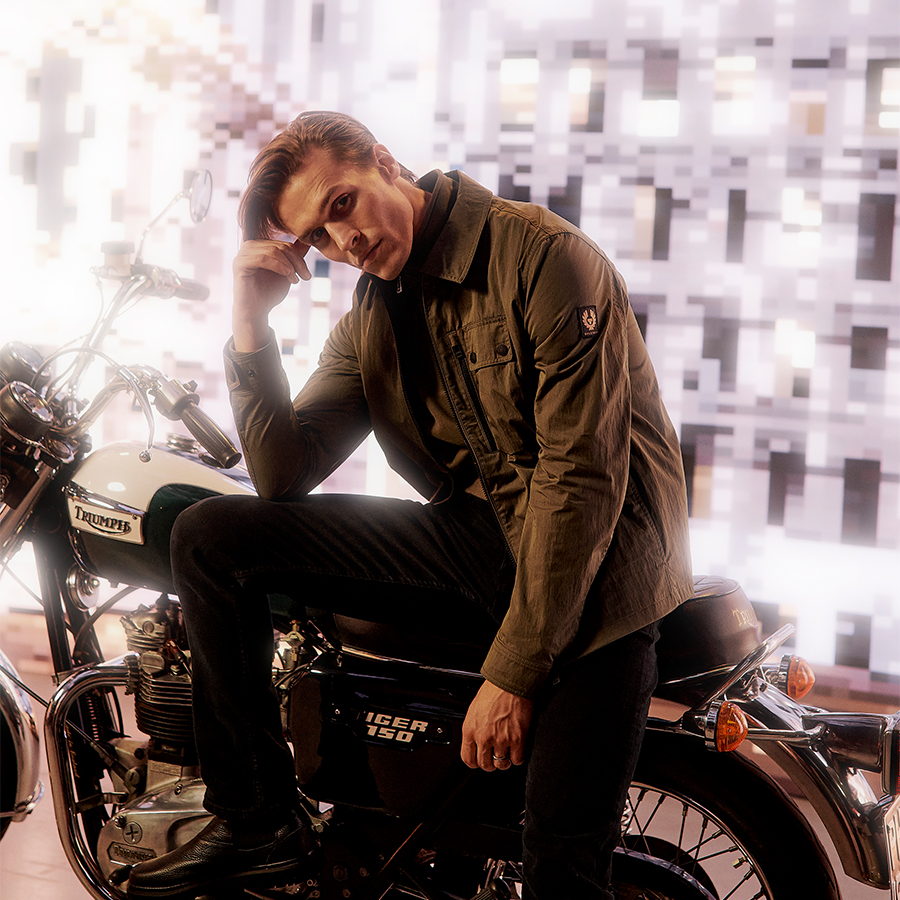A man sits on a motorbike wearing smart casual clothes