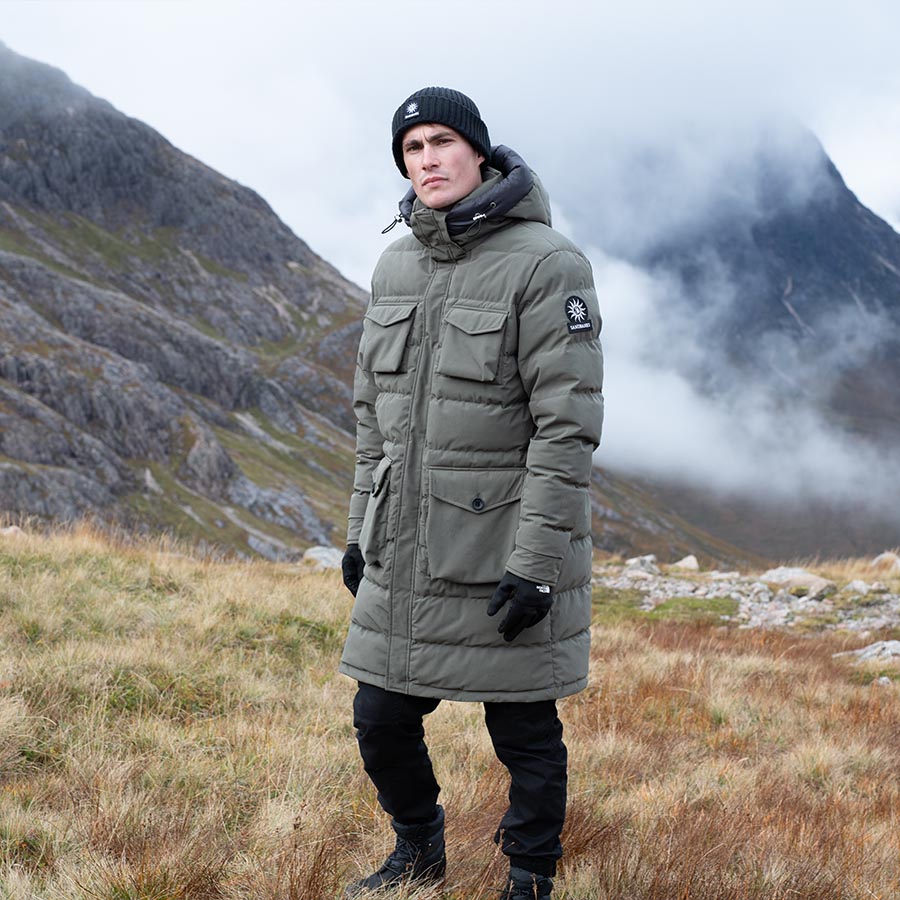 A man standing in the hills wearing a long Sandbanks coat