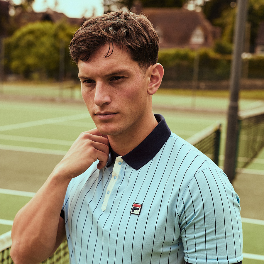 A man dressed in Fila standing on a tennis court