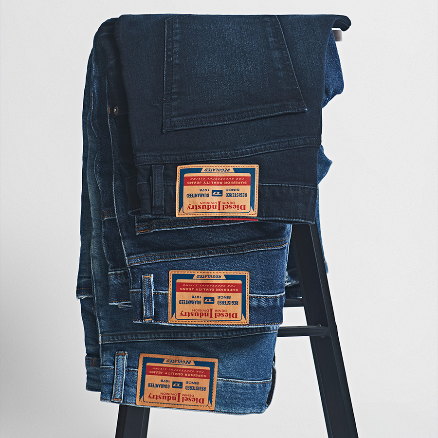 Three pairs of Diesel jeans hanging up on a stool