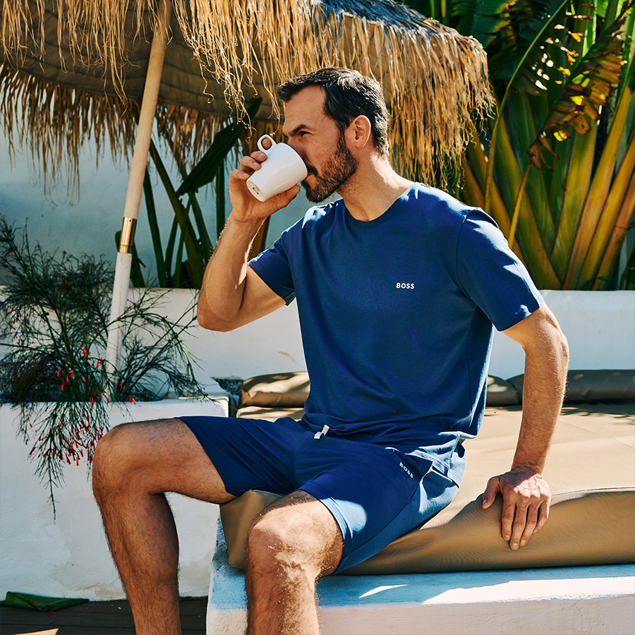 A dad sitting in the sun drinking coffee