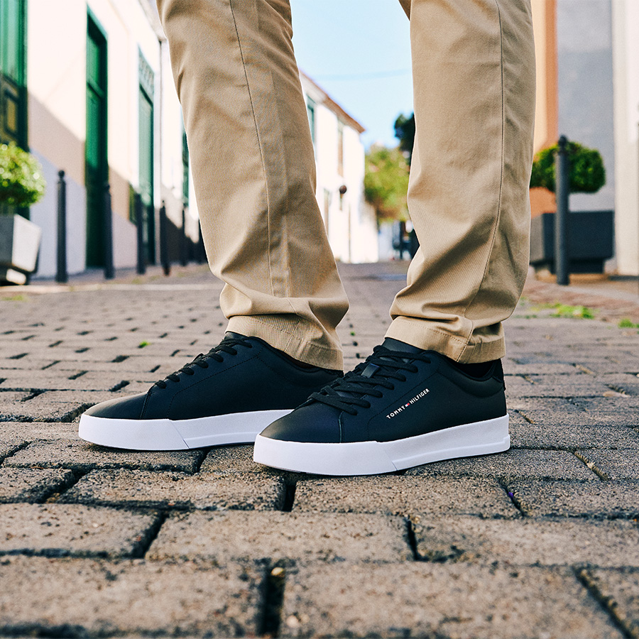 A pair of legs in beige trousers and trainers
