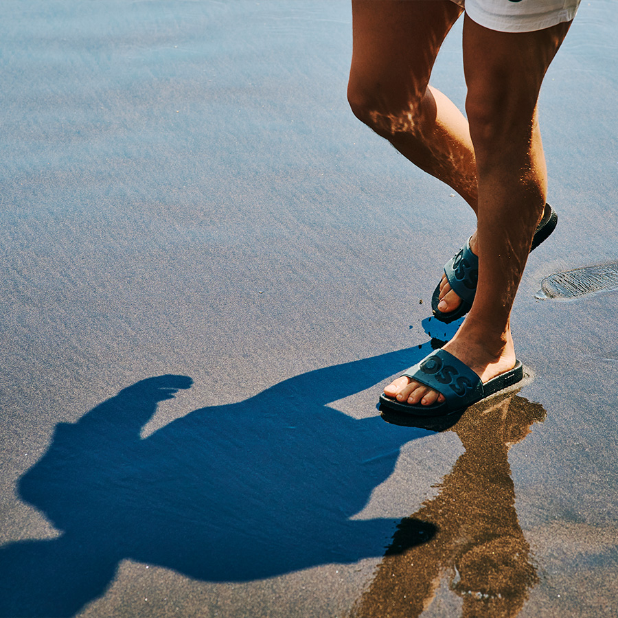 A man walking on the beach in sliders