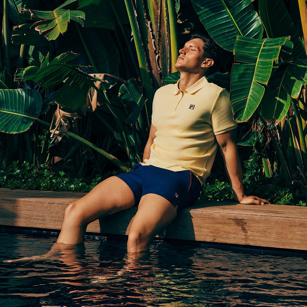 A man relaxing by the pool with his feet in the water